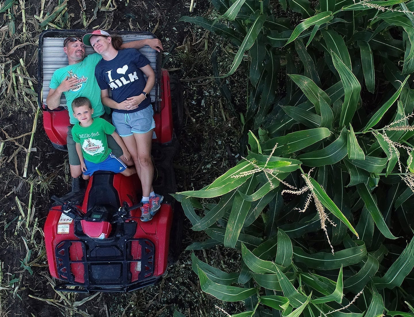 Farmer Blake Hansen, his wife Jordan and their son Beckett rest on a ATV in their farm's corn field.