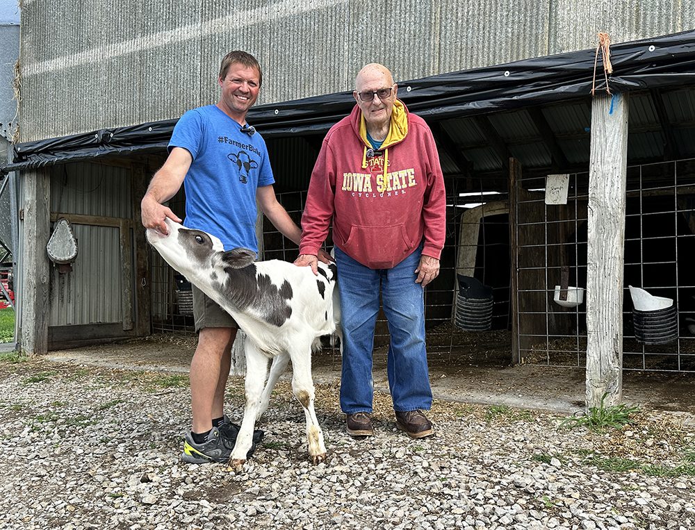 Hadwen Kleiss stands with Blake Hansen and a calf that was produced with semen from Kleiss's prized bull of the 1980s.