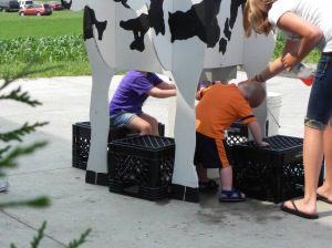 Kids try their hand at milking our wooden cow!